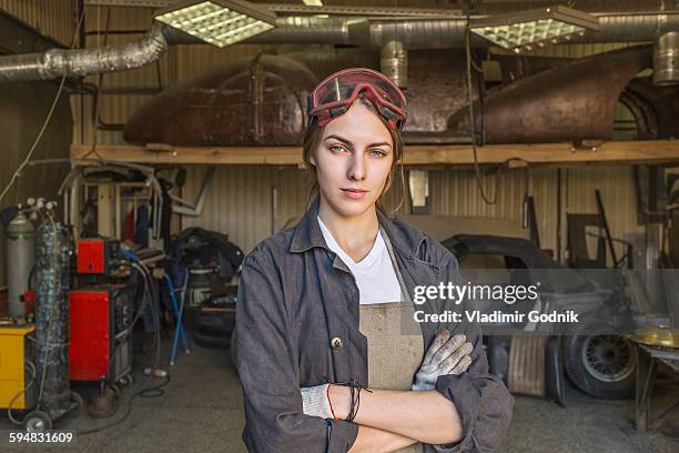 portrait of confident female mechanic with arms crossed at garage - mechanic arms crossed stock pictures, royalty-free photos & images