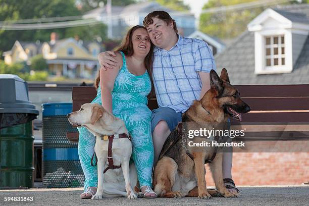 blind couple hugging each other with their service dogs relaxing at a bench on the beach - love is blind stock-fotos und bilder