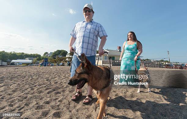 blind couple with their service dogs walking along the beach - guide dog at work stock pictures, royalty-free photos & images