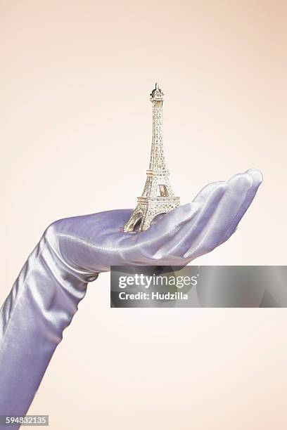 cropped hand of bride holding eiffel tower model against colored background - formal glove stock pictures, royalty-free photos & images