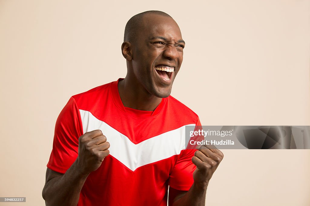 Excited soccer player cheering against colored background