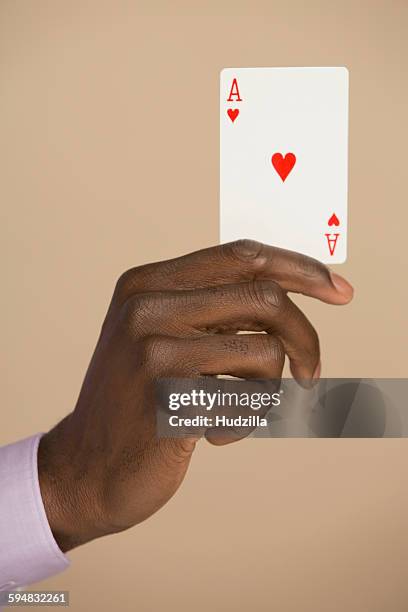 cropped hand holding ace card against colored background - kartenspiel stock-fotos und bilder