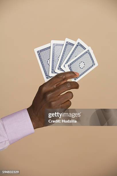 cropped hand holding playing cards against colored background - hand of cards stock-fotos und bilder