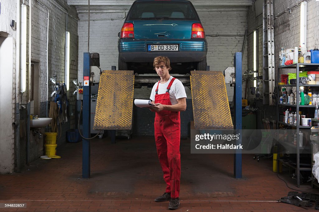 Portrait of confident mechanic holding clipboard at garage