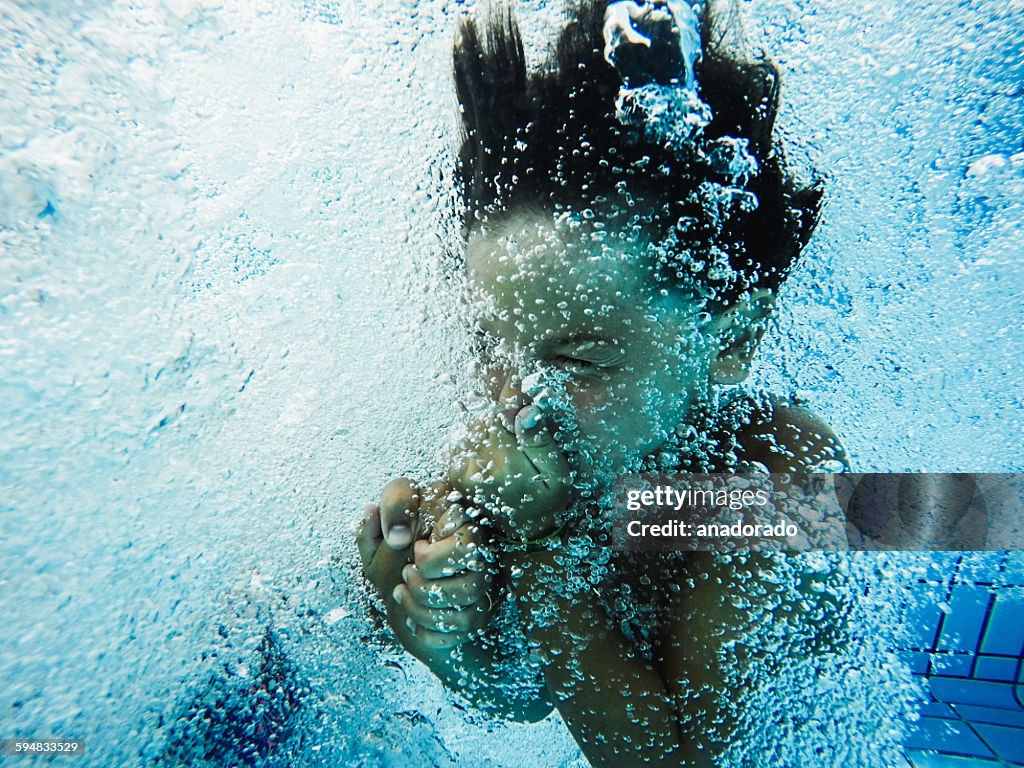 Boy holding his nose, jumping into a swimming pool