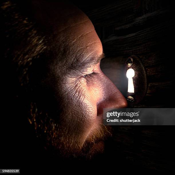 man looking through a keyhole in a door - looking through keyhole stock pictures, royalty-free photos & images