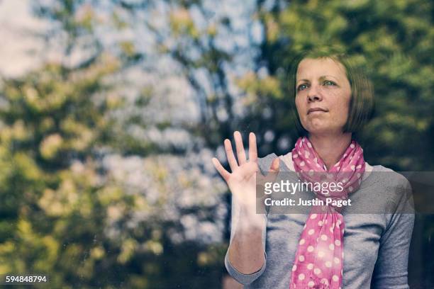 woman waiting in window - afgesloten ruimte stockfoto's en -beelden
