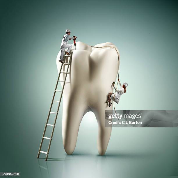 small man and woman work on the outside of large tooth - toothache stock-fotos und bilder
