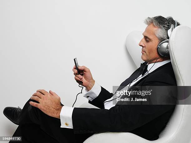 man listening to mp3 player in tuxedo - classical stockfoto's en -beelden