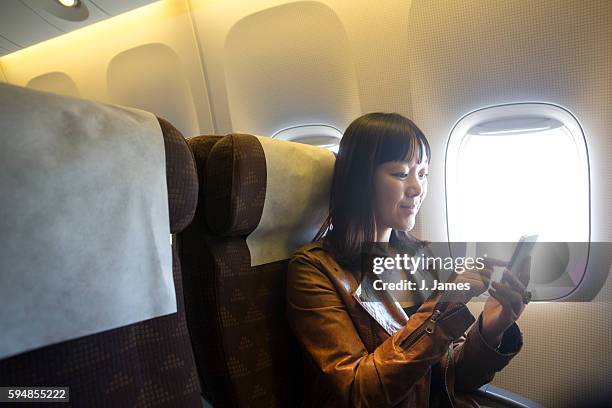 woman using mobile phone in airplane - plane passenger stock pictures, royalty-free photos & images