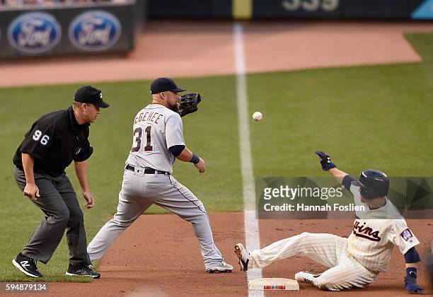 Brian Dozier of the Minnesota Twins slides safely into third base as Casey McGehee of the Detroit Tigers fields the ball as umpire Chris Segal looks...