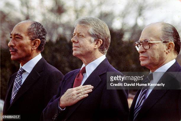 Egyptian President Anwar al-Sadat, US President Jimmy Carter, and Israeli Premier Menachem Begin listen to the national anthem before signing the...