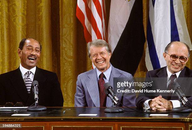 Egyptian President Anwar al-Sadat, US President Jimmy Carter, and Israeli Premier Menachem Begin laugh together during the signing the Camp David...