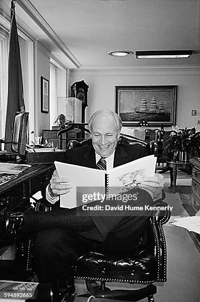 Vice President Dick Cheney laughs while reading a collection of Pluggers panel comics in his office circa 2001 in Washington, DC.