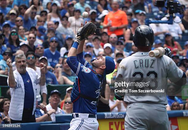 Josh Thole of the Toronto Blue Jays catches a foul pop up in the fourth inning during MLB game action as Nelson Cruz of the Seattle Mariners watches...