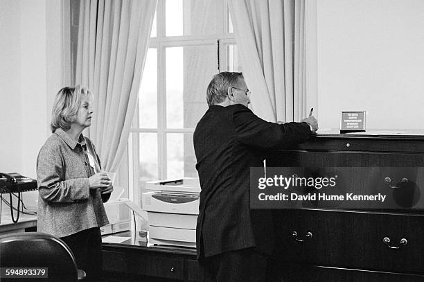 Secretary of Defense Donald Rumsfeld writes as his personal secretary looks on in his Pentagon office on September 5, 2002 in Washington, DC.