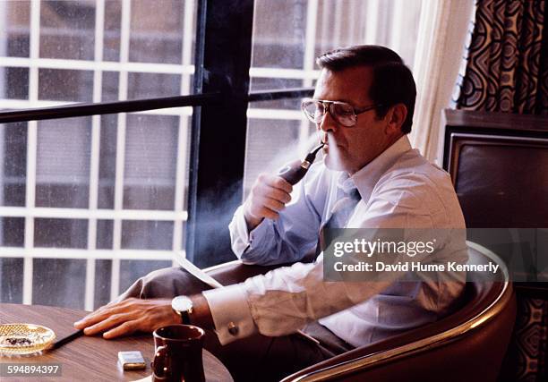 Former Secretary of Defense Donald Rumsfeld smokes his pipe in his hotel room during the 1980 Republican National Convention, July 1980 in Detroit,...