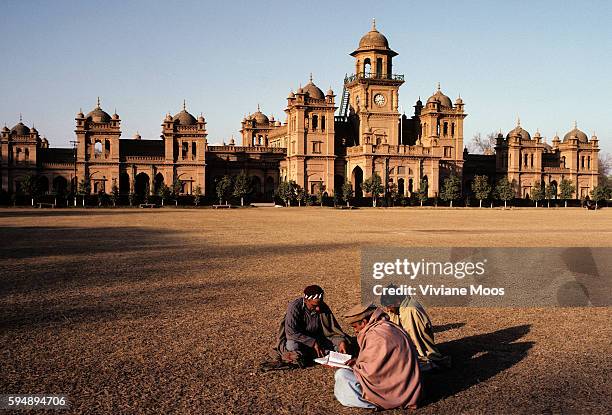 Three men studying on the lawn of the University of Peshawar.