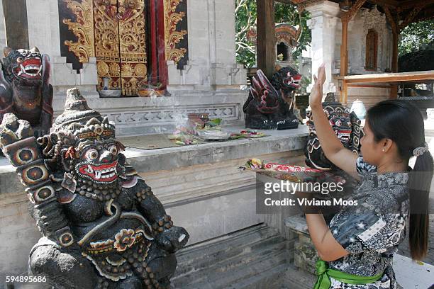 Young woman offers prayers and flowers to the gods and spirits at the Pura Semawang temple.