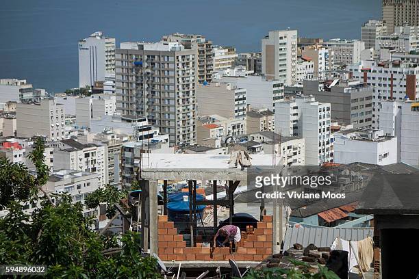 View from the Favela Cantagalo of the contrast between rich and poor; building an additional room on top of the home in the traditional way of the...