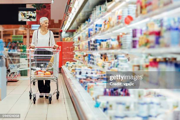 mature woman groceries shopping. - shopping trolley supermarket stock pictures, royalty-free photos & images