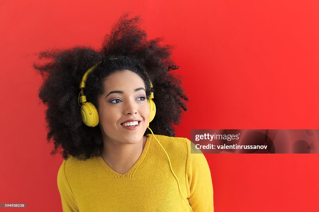 Young woman listening music with yellow headphones