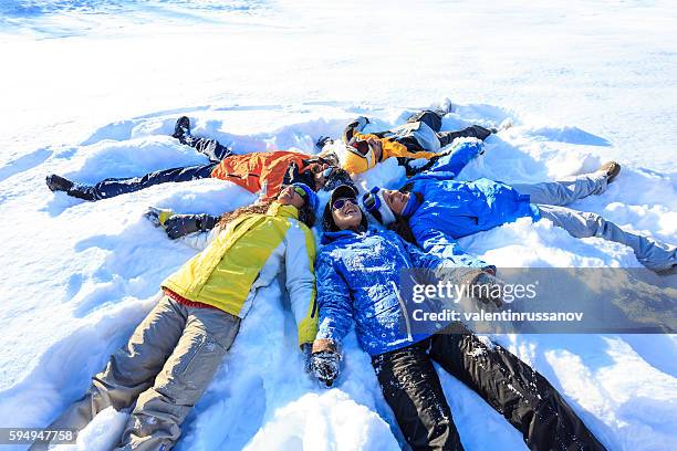 gruppe junger leute, die schneeengel machen - winter friends playing stock-fotos und bilder