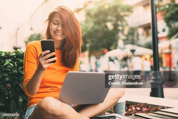 mujer enviando mensajes de texto al aire libre - redhead teen fotografías e imágenes de stock