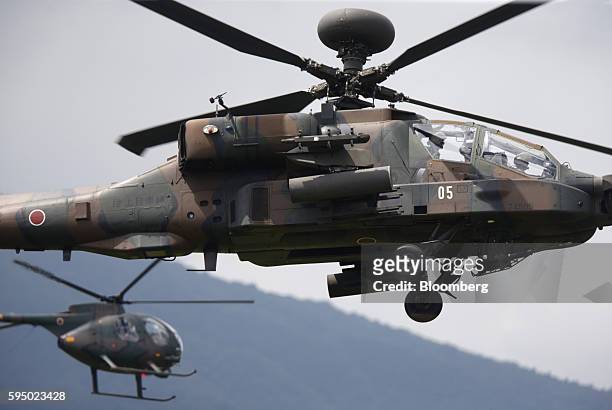 Japan Ground Self-Defense Force AH-64D Apache Longbow attack helicopter, front, flies during a live fire exercise at the foot of Mount Fuji in the...