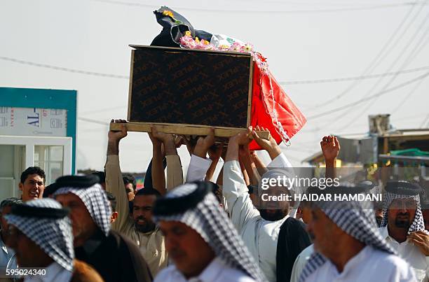 Iraqis carry a coffin during the funeral of members from the Iraqi government forces and Shiite fighters from the Popular Mobilization units, who...