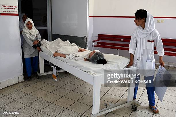 Afghan doctors move a wounded Afghan girl student from the American University after she received treatment, following the militants' raid that...