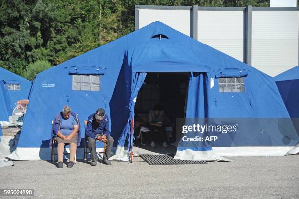 People sit on chairs outside tents of a temporary camp in Pescara del Tronto on August 25 a day after a 6.2-magnitude earthquake struck the region...