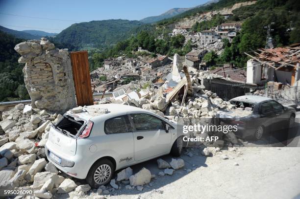 Cars sit amidst the rubble from earthquake damaged buildings in the central Italian village of Pescara del Tronto on August 25,2016 a day after a...