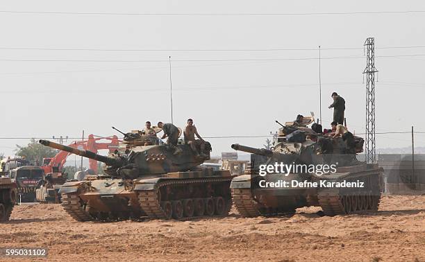 Turkish soldiers stand on tanks as they prepare for a military operation at the Syrian border town of Karkamis in the southern region of Gaziantep,...