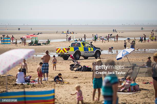 Police drive along Camber Sands on August 25, 2016 in Rye, England. Five men were found dead after being pulled from the sea on the hottest day of...