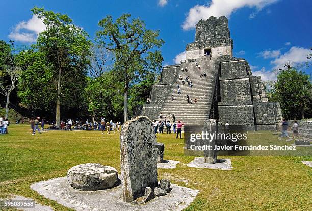 stelae, altars and temple ii or temple of the masks located in the great square of the maya city of tikal, surrounded by numerous national and international tourists, who enjoy the greatness of this important enclave of mayan culture. - tikal stock pictures, royalty-free photos & images