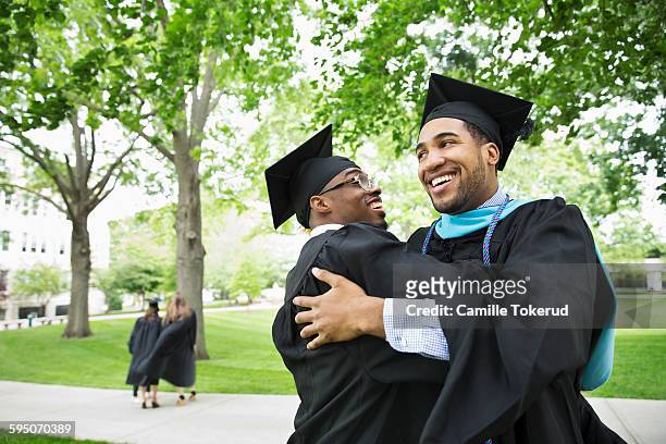 college male graduates hugging and smiling - college graduation ストックフォトと画像
