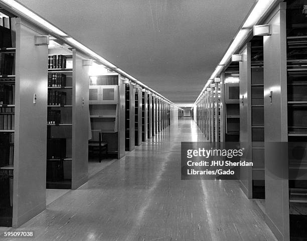 Long, vacant hallway with stacks of books on an underground level inside the Milton S Eisenhower Library at Johns Hopkins University, Baltimore,...