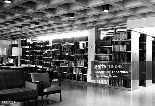 On an underground reading and study level inside the Milton S Eisenhower Library at Johns Hopkins University, stacks of books stand next to tables...