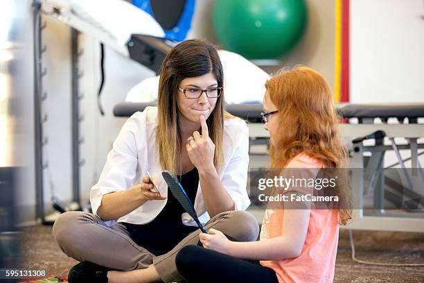 young female speech therapist helping a young patient - speech therapy imagens e fotografias de stock