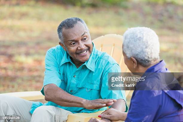 senior african american man looking at wife - adirondack chair closeup stock pictures, royalty-free photos & images
