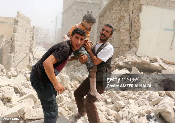 Syrians carry a wounded child in the rubble of buildings following a barrel bomb attack on the Bab al-Nairab neighbourhood of the northern Syrian...