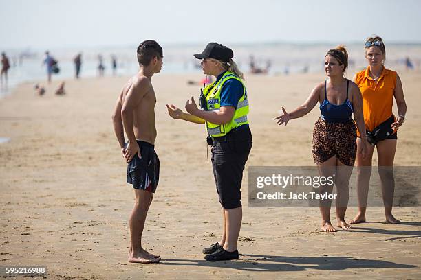 Police officer advises a swimmer to come in as the tide moves in on Camber Sands on August 25, 2016 in Rye, England. Five men were found dead after...