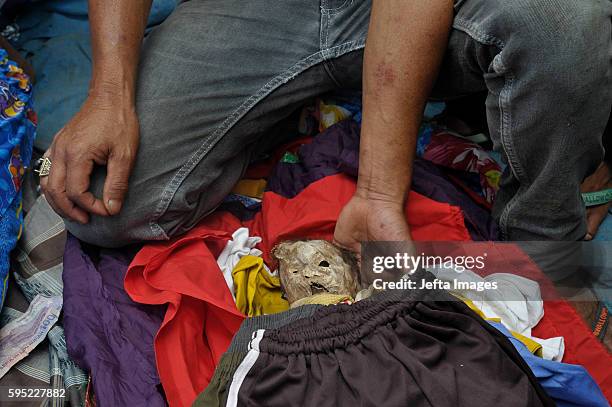 Family members cover bodies of deceased by clothes during Manene ritual on August 25, 2016 in Toraja, Indonesia. The Manene ritual involves changing...