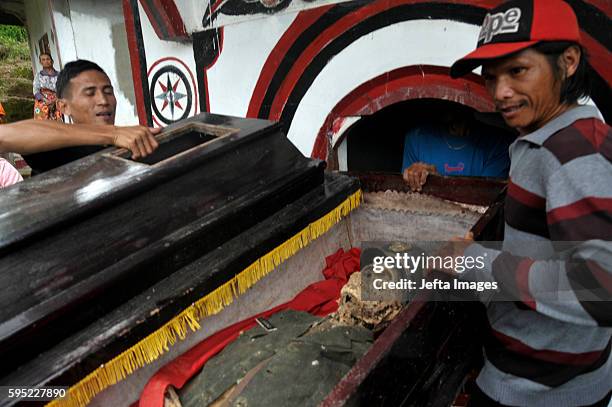 Family members cover bodies of deceased by clothes during Manene ritual on August 25, 2016 in Toraja, Indonesia. The Manene ritual involves changing...