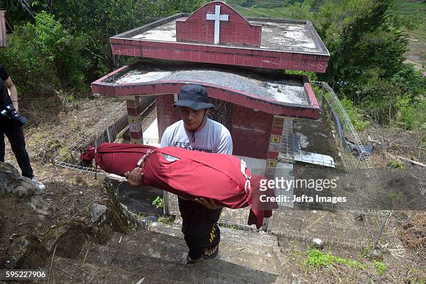 Family members cover bodies of deceased by clothes during Manene ritual on August 25, 2016 in Toraja, Indonesia. The Manene ritual involves changing...