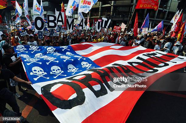 Philippines - Protesters spread out a mock US flag containing the words "Obama Out!" as they march towards one of the gates of the Presidential...