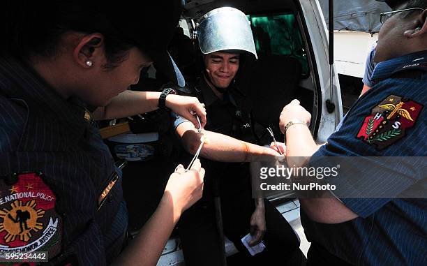 Philippines - A police officer receives first aid after acquiring minor injuries after clashing with protesters, as they attempt to march towards the...