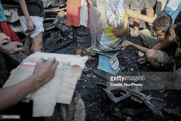 Residents weigh a sack of scrap metal collected from burned houses in suburban Quezon city, northeast of Manila, Philippines, April 6, 2014. Around...