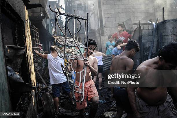 Resident carries a metal frame past burned houses in suburban Quezon city, northeast of Manila, Philippines, April 6, 2014. Around 50 houses were...